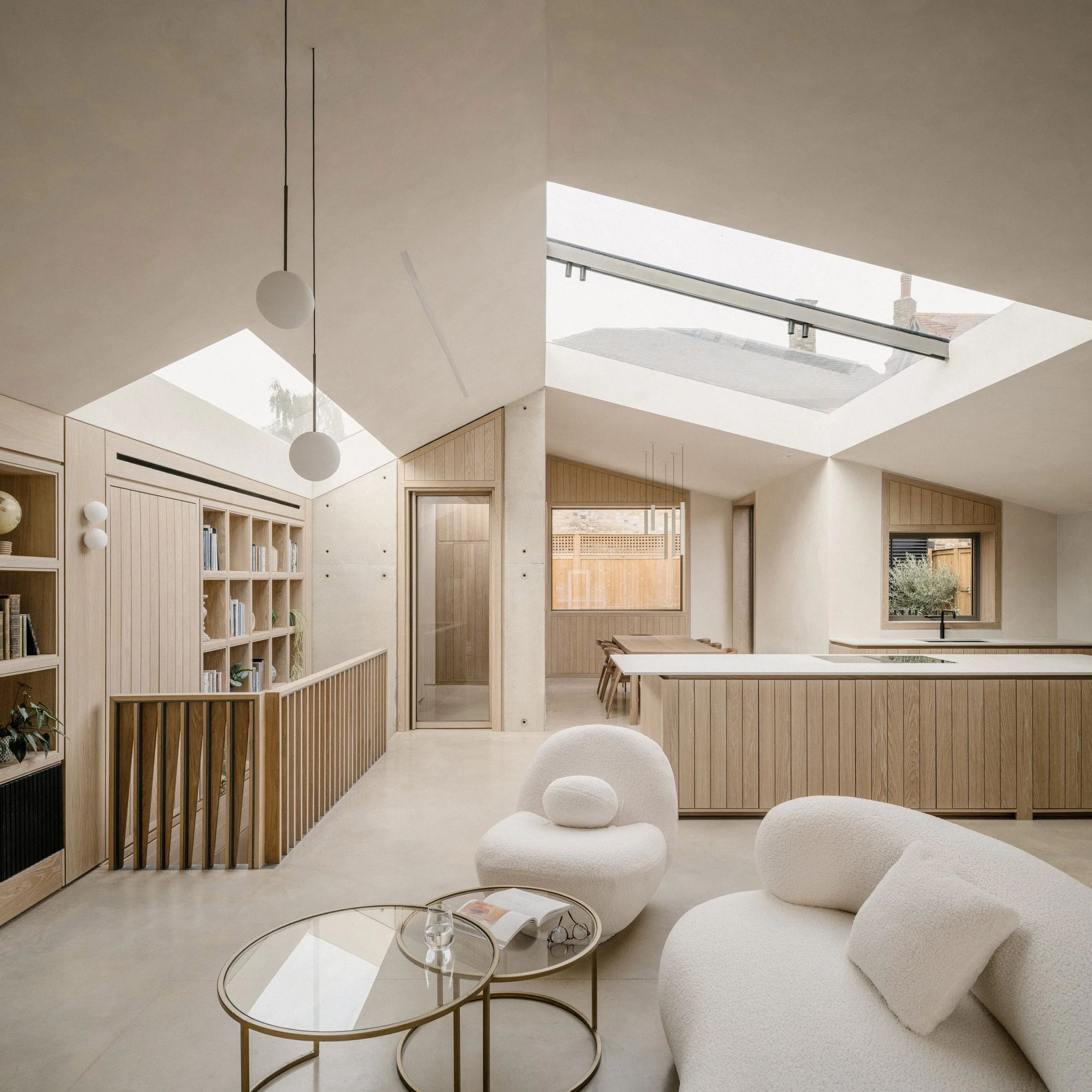 Open-plan living area with large rooflights, oak cabinetry and exposed concrete walls