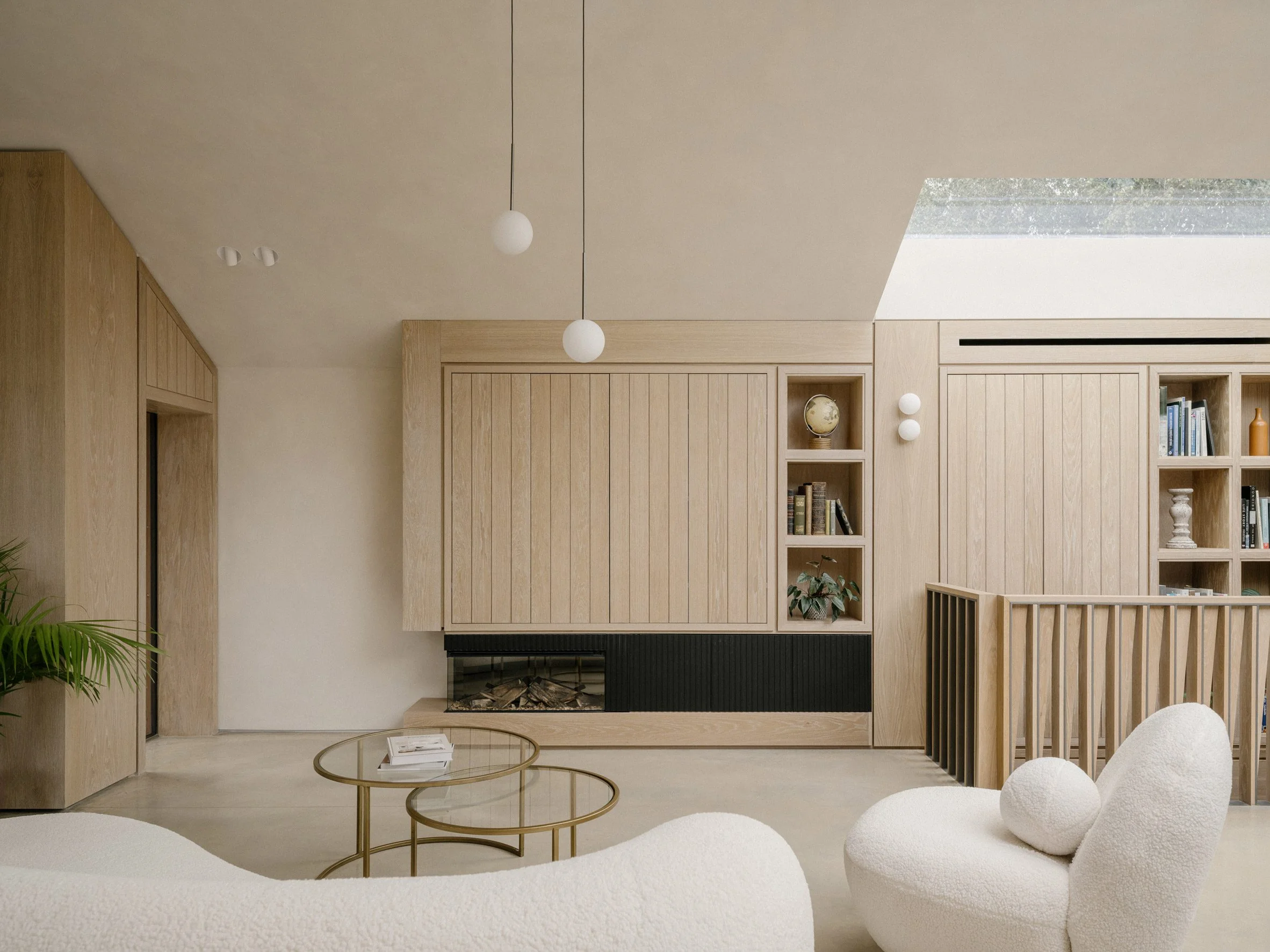 Living room with built-in oak storage and seating arranged beneath the asymmetrical roof form