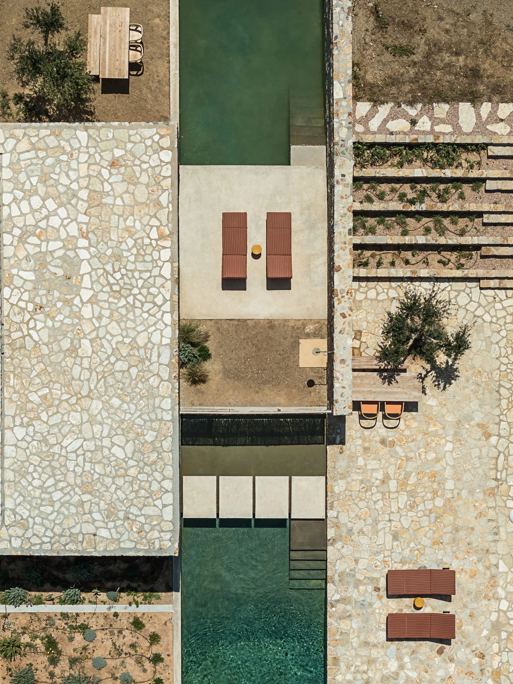 Overhead view of a swimming pool, stone terraces and planted landscape